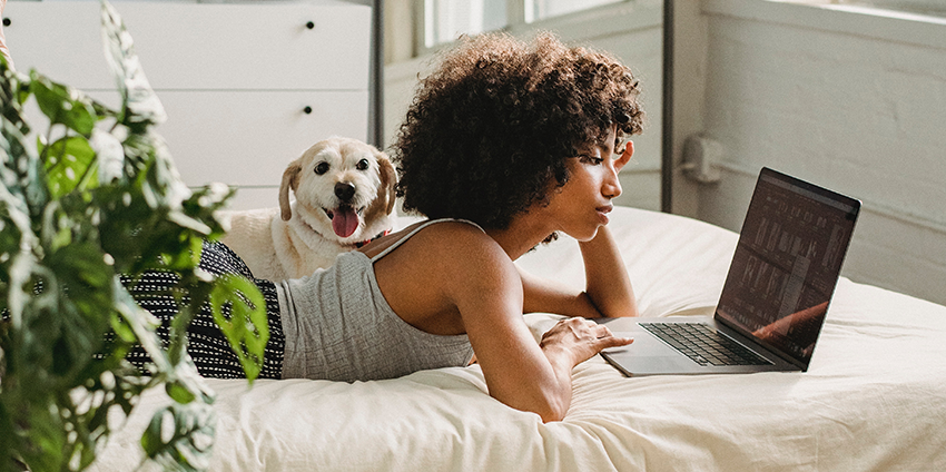 Meisje ligt op bed met laptop met hond